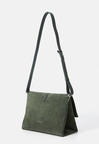 Borsa in suede verde con forma piegata, tracolla regolabile e hardware in argento. Presenta un logo discreto sul pannello frontale.