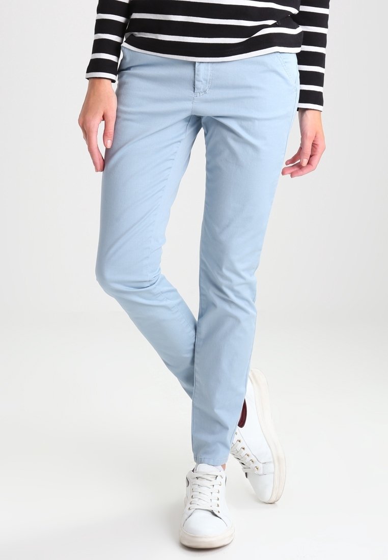 Ljusblå bomullschinos med en slim-fit design, kombinerat med vita sneakers. Toppdelen har svarta och vita ränder.