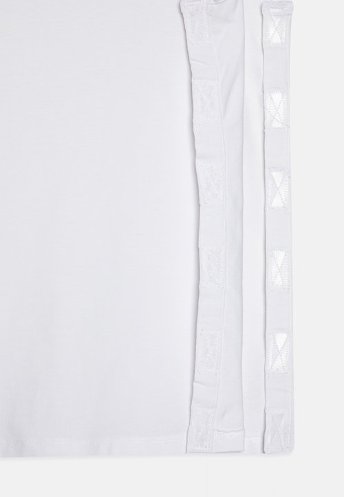 T-shirt bianco con una texture liscia e un bordo in pizzo decorativo lungo entrambi i lati, accentuato da ritagli a motivo diamante.