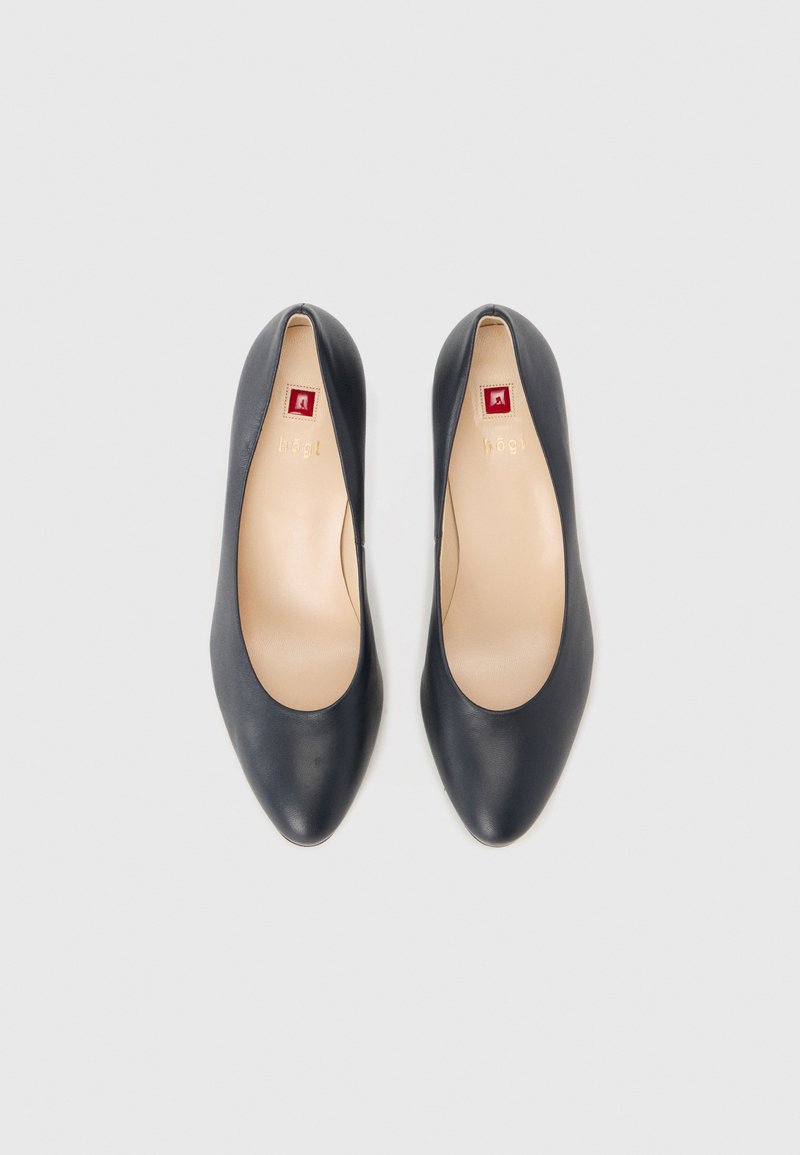 Para czarnych skórzanych baletek z zaokrąglonym noskiem i beżowymi wkładkami, pokazana z góry na białym tle.