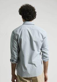 Camisa a cuadros azul claro con mangas largas, puños doblados y cuello abotonado, que presenta una textura suave y un corte relajado.