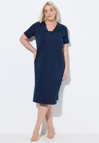Camicia da notte blu navy realizzata in tessuto morbido, con maniche corte, scollatura a V con finitura decorativa e aperture laterali per facilitare i movimenti.