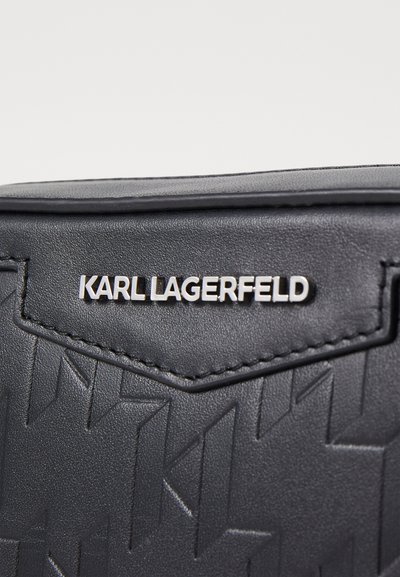Черна текстурирана кожена чанта с релефен геометричен модел. Сребристото лого "KARL LAGERFELD" е из prominently displayed на предната част.