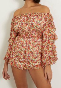 Combinaison à épaules dénudées avec de longues manches à volants. Présente un motif floral coloré en orange et rose sur un fond clair.