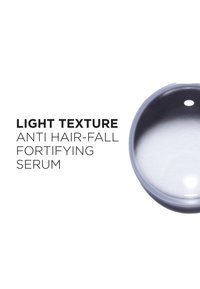 Serum med lett tekstur i en gjennomsiktig flaske, merket "Anti Hair-Fall Forsterkende Serum," med en glatt, blank finish.