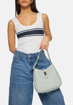 Groene leren schoudertas met een ronde vorm, gouden hardware details en een gestructureerde afwerking, vastgehouden door een persoon in high-waisted denim shorts.