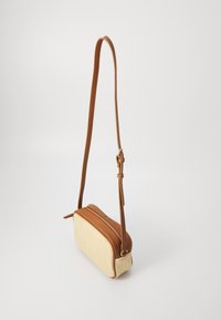 Crossbody tas met een beige geweven textuur en bruine leren accenten. Voorzien van een ritsluiting en een verstelbare schouderband. Rechthoekige vorm.