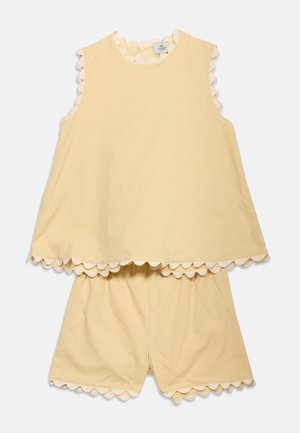 Yellow sleeveless top and matching shorts with scalloped edges on sleeves, hem, and shorts, laid flat on a light background.