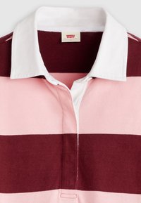 Μπορντό και ροζ ριγέ πόλο πουκάμισο με λευκό γιακά, με πατιλέτα με κουμπιά. Το ύφασμα φαίνετα ι μαλακό και πλεκτό με ορατή υφή.