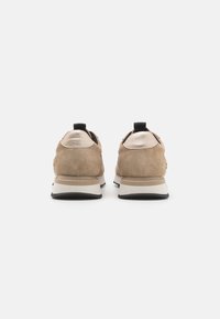 Beige semskinns sneakers med glatte skinnaksenter, med en svart hæltab og hvit såle. Polstret design med teksturert overdel.