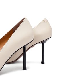 Beżowe skórzane szpilki o smukłej formie, z czarnymi obcasami typu stiletto i minimalnymi detalami szwów.