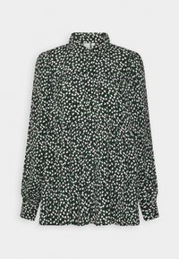 Blouse noire avec un col chemise, présentant de petits motifs floraux blancs et verts, manches longues et un design fluide à plis.