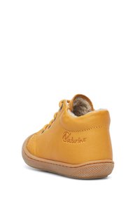 Žlutá kožená bota s měkkým interiérem, tkaničkovým designem a gumovou podrážkou. Obsahuje šitou šev a vyražené logo na boku.