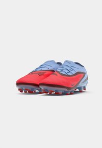 Bottes de football Nike avec un design dégradé, dotées d'un dessus rouge et d'accentuations bleu clair, en matériau texturé et avec une semelle extérieure à crampons en caoutchouc.