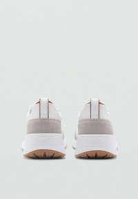 Weiß-beige Sport Schuhe verfügen über ein glattes Stoffobermaterial, Wildlederakzente, eine auffällige Fersenschlaufe und eine strukturierten Sohle mit Branding auf der Rückseite.