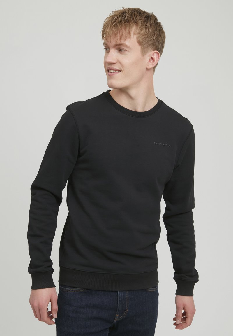Fekete, pamut keverékből készült pulóver, crew neck-kel, hosszú ujjakkal, bordás mandzsettákkal és egy kis logóval a mellkasán. Laza fazon.