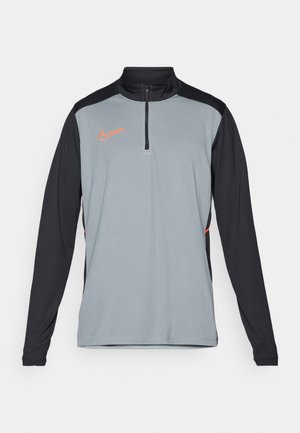 Nike Langarm-Trainingstop in Hellgrau und Schwarz, mit einem Viertelreißverschluss, kontrastierenden Seitenstreifen und einem orangefarbenen Logo auf der Brust.