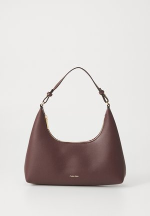 Maroon handbag with a curved silhouette and a short strap, featuring a gold zipper and a subtle Calvin Klein logo on the front.
