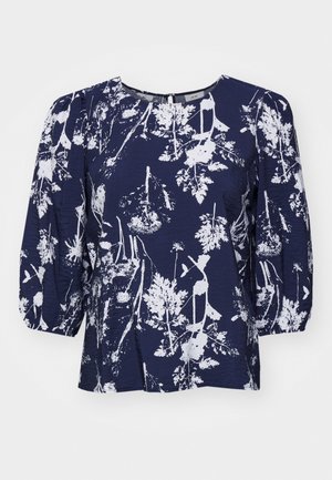 Námornícky modrá blúzka s bielou botanickou potlačou, okrúhlym výstrihom a puffovanými rukávmi. Textúrovaná látka s voľným strihom a jemným leskom.