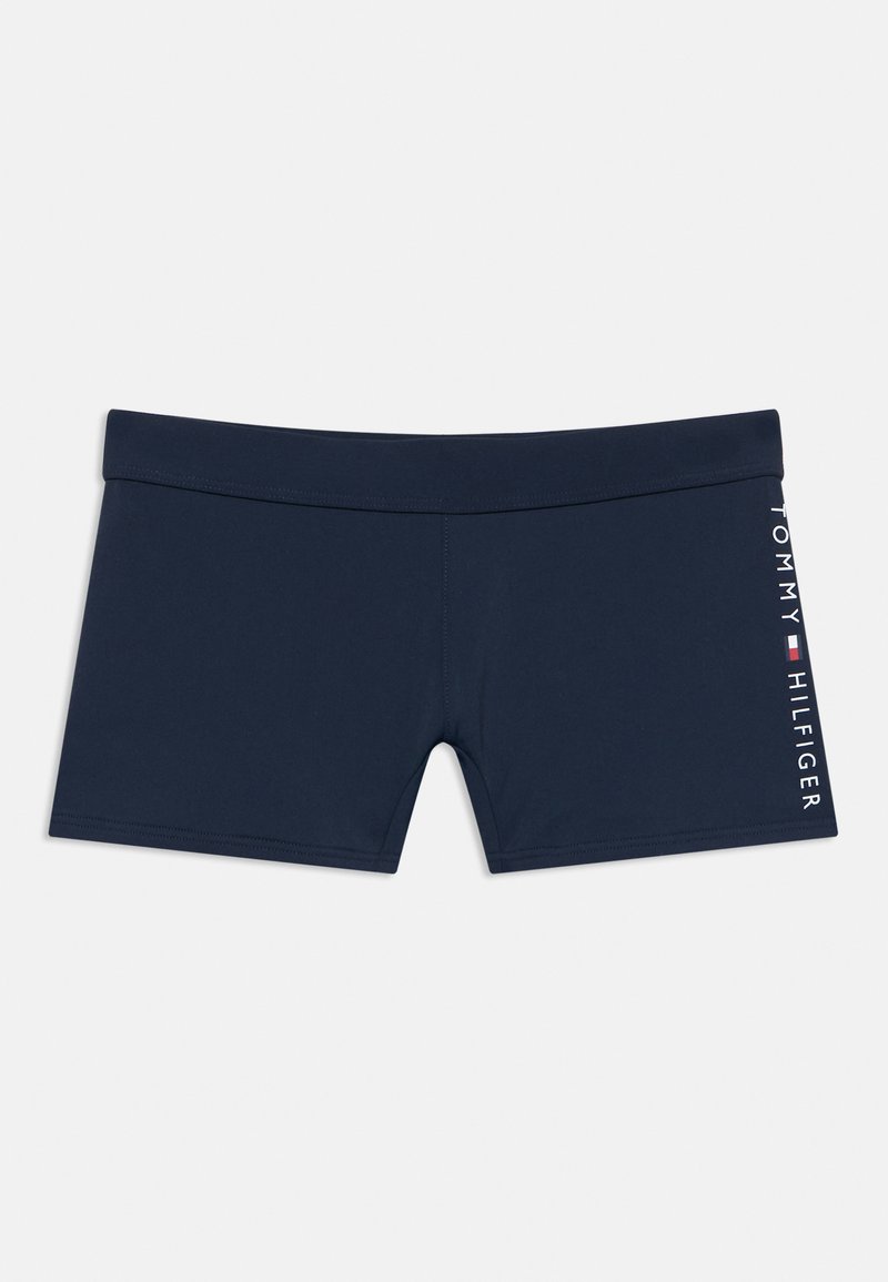 Μαγιό σορτς σε ναυτικό μπλε χρώμα, κατασκευασμένο από μαλακό, ελαστικό ύφασμα με μονόχρωμο σχέδιο. Στην πλευρά είναι τυπωμένο το λευκό λογότυπο "TOMMY HILFIGER".