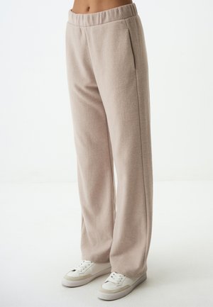 Lichtbeige, zachte, fleecebroek met een elastische tailleband en zijzakken, gecombineerd met witte sneakers voor een casual look.