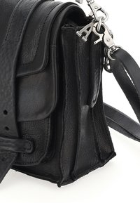 Crna kožna torbica s teksturiranom površinom, strukturiranim oblikom, metalnim dodacima i podesivim remenom. Ima više pregrada.