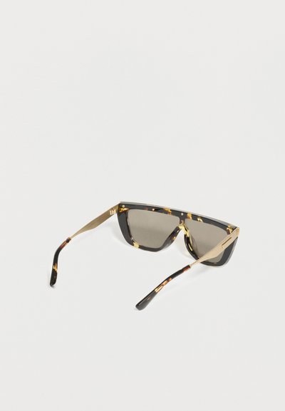 Γυαλιά ηλίου με σκελετό χοιρόδοντο και χρυσό, με ορθογώνιους χρωματιστούς φακούς, γωνιακά μπράτσα και μοντέρνο, τολμηρό σχέδιο σε λευκό φόντο.