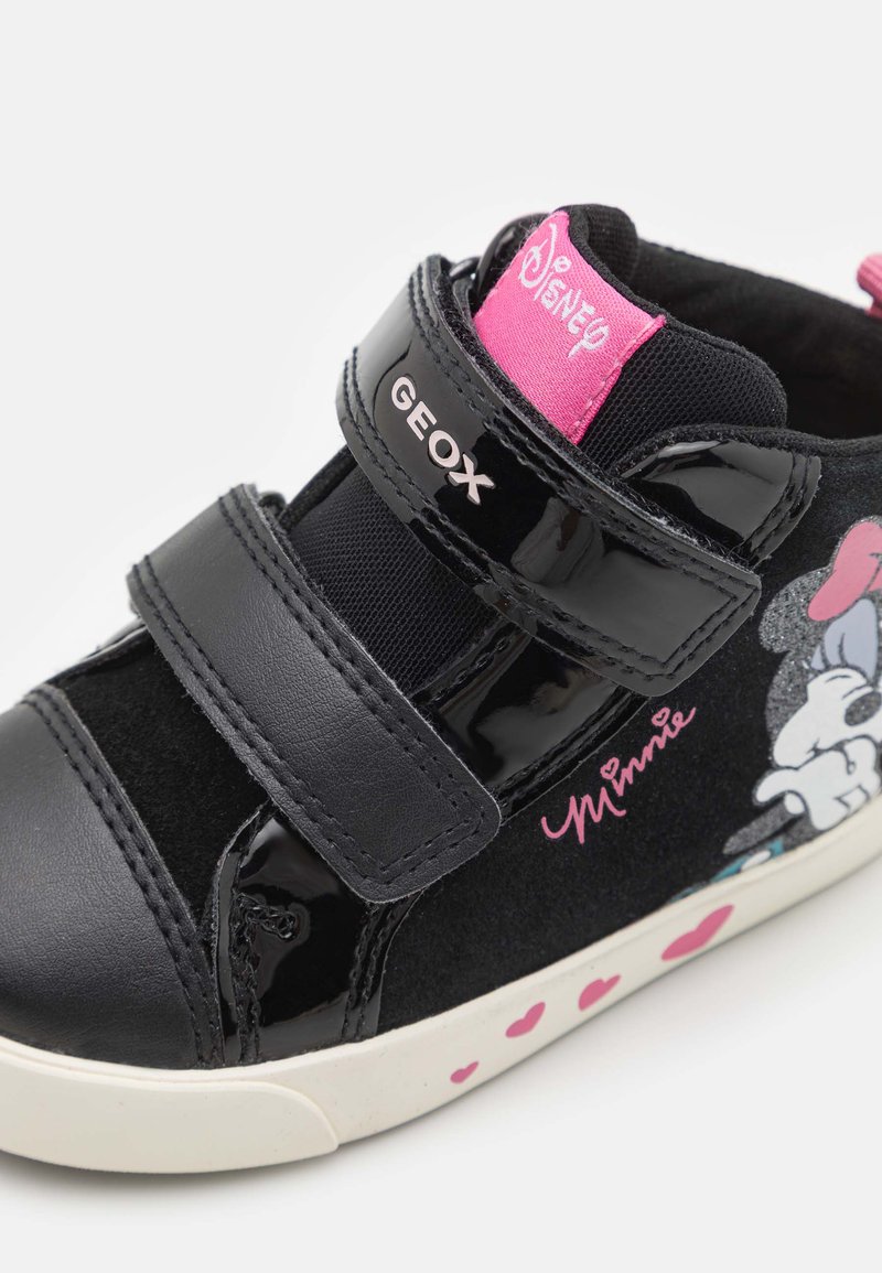 Zwart gepatineerd leren sneaker met klittenbandsluiting, roze accenten en een Minnie Mouse afbeelding. De witte zool heeft roze hartpatronen.