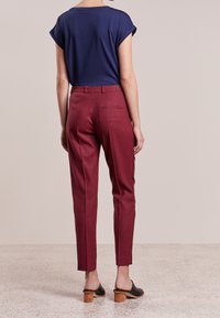 Haut bleu marine à manches courtes associé à un pantalon à carreaux rouges, taille ajustée, poches latérales, et chaussures noires à enfiler avec un talon en bois.