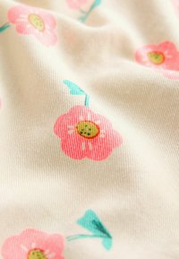 Tessuto di cotone floreale con fiori rosa e foglie teal su uno sfondo crema, caratterizzato da una superficie morbida e texture leggermente rigata.