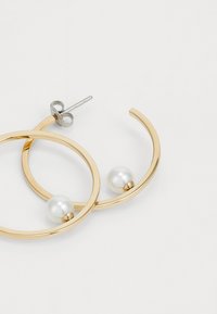 Orecchini a cerchio dorati con due perle bianche, design circolare con finitura liscia e hardware in argento per il gambo e il retro.