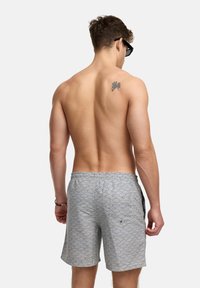 Grå svømmeshorts med bølgemønster, elastisk liv, og sidelommer. Stoffet har en glatt tekstur og lett design.