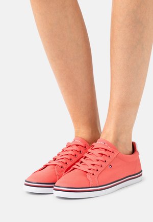 Korallfärgade kanvas sneakers med vita gummisulor. Har snörning, logotyp på tungan och subtila sidostygn med röda och blå detaljer.