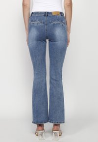 Uppvikta blå jeans med en mjuk denimtextur, midjehöjd och två bakfickor. Försedda med en beige läderlappar på midjebandet.