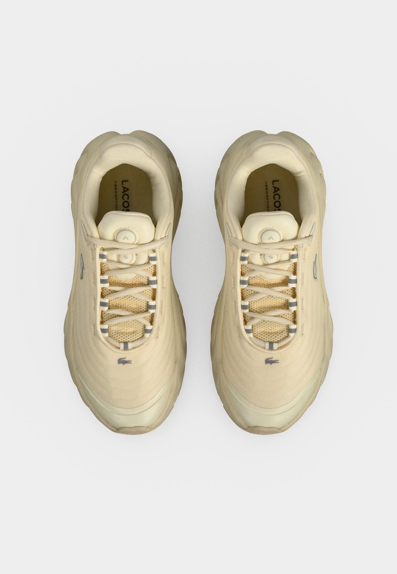 Coppia di sneaker beige Lacoste con lacci, texture in mesh e logo sulla linguetta e sul lato, viste dall'alto su sfondo bianco.