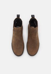 Brown leather ankle boots with a smooth texture, elastic side panels, and a pull tab at the back, featuring a rounded toe and flat sole.