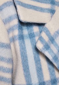 Villakangas sekoitekankainen takki, jossa on sinivalkoinen raidallinen kuvio, pehmeä rakenne ja pyöreät kaulukset. Reunat ovat hieman rispaantuneet.