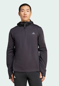 Schwarzer leichter Pullover mit Halb-Zipperkragen, Kapuze und reflektierenden Akzenten. Verfügt über lange Ärmel mit Daumenlöchern und einem strukturierten Stoff.