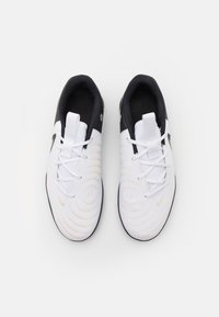 Witte sportieve schoenen met een getextureerd, spiraalpatroon. Zwarte accenten bij de hiel en tong. Standaard vetersysteem met een trekknoop.