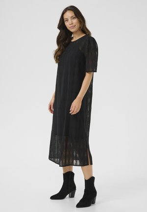 Black lace midi dress with short sleeves, featuring a diamond pattern and side slits. Paired with black ankle boots.