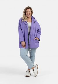 Violet raincoat su kapišonu, užtrauktukais ir viršutine juosta su raišteliais. Dėvima virš baltos bluzos ir derinama su šviesiai mėlynomis džinsais bei sportbačiais.