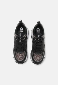 Czarne sneakersy z metalicznym wzorem, z teksturowaną siateczką na górze, sznurówką i grubą białą podeszwą dla dodatkowego wsparcia.