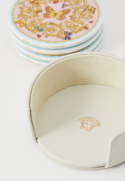 Nosilec za kozarce iz belega usnja s semišasto notranjostjo. Vključuje zlato vtisnjen Medusin logotip. Vsebuje barvne podstavke z vzorcem.