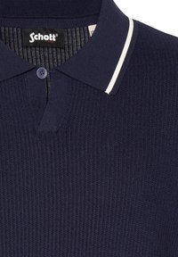 Polo de punto azul marino con una raya blanca en el cuello, un solo botón azul marino y etiqueta de la marca Schott NYC negra en el interior del cuello.