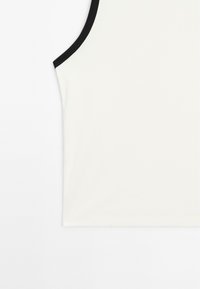 White tank top with a black ribbed neckline. Smooth, soft fabric features a fitted design, no visible patterns or additional accents.