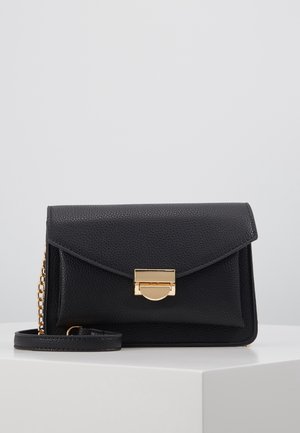 Schwarze, strukturiert geprägte Leder-Umhängetasche mit goldenem Verschluss und Kettendetail, präsentiert auf einer weißen Oberfläche vor einem schlichten grauen Hintergrund.