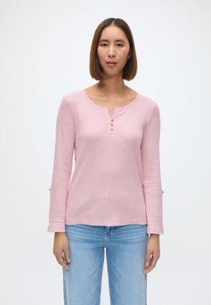 Helles rosa Langarmshirt mit Henley-Ausschnitt, das drei Knöpfe und eine dezente gerippte Textur aufweist. Die Ärmel enden am Handgelenk mit kleinen Akzenten.
