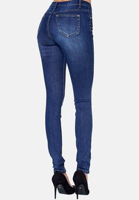 Skinny denim jeans in dark blue with a smooth texture, featuring a high waist, back pockets, and subtle stitching details.