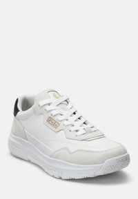 Vita läder- och mockaskor med en texturerad ovandel, plana vita snören och en marinblå detalj vid hälen. Guld "Polo"-logga på sidan.