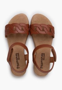 Sandali in pelle marrone con design della cinghia intrecciata, soletta in sughero e cinghia regolabile alla caviglia. Superficie testurizzata e suola piatta.